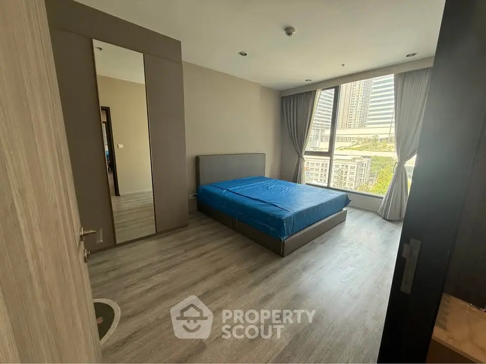 Spacious bedroom with large window and city view in modern apartment