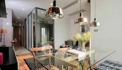 Modern open-plan living and dining area with stylish lighting and glass table.