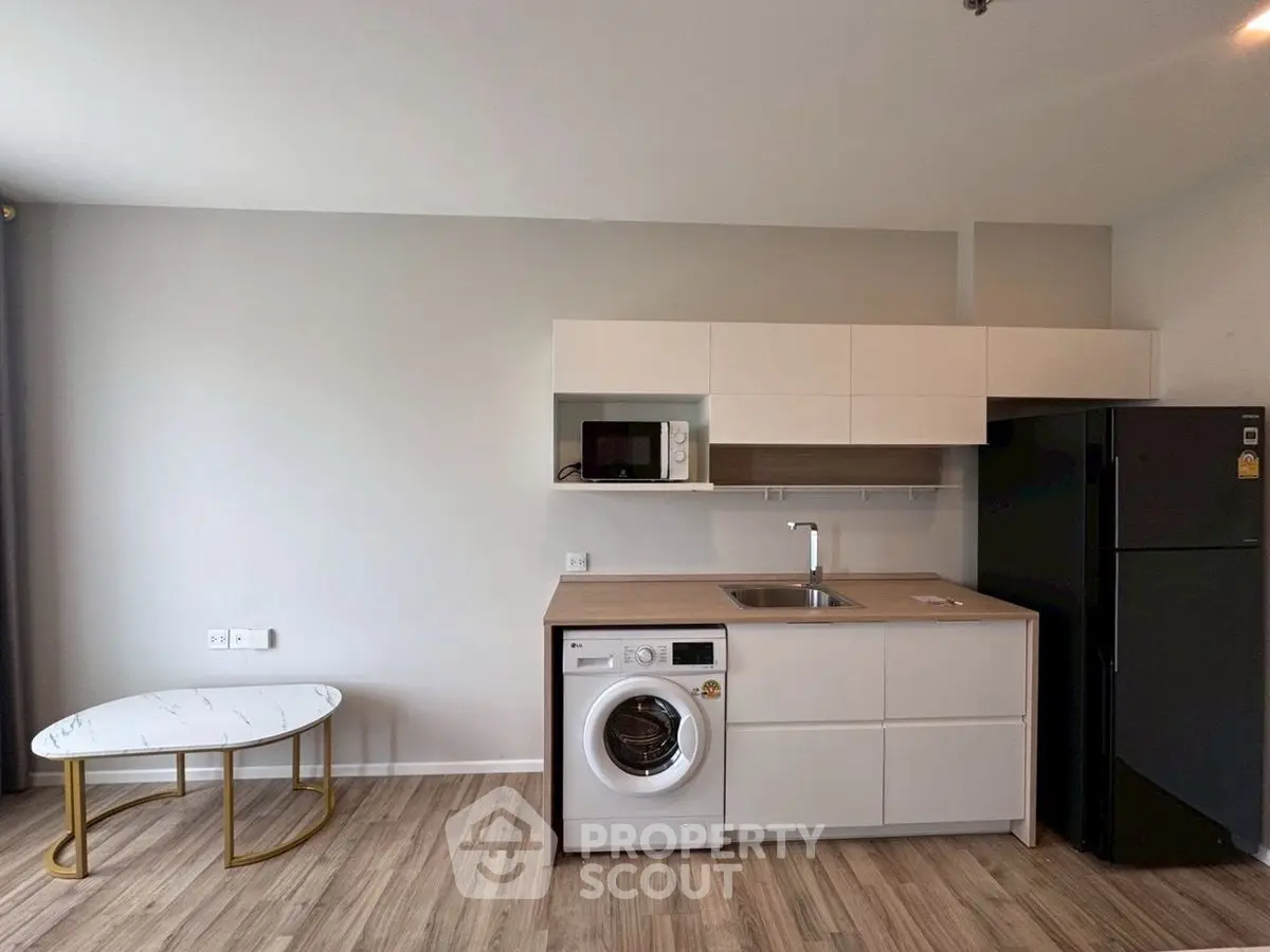 Modern kitchen with washing machine and sleek cabinetry in a stylish apartment.