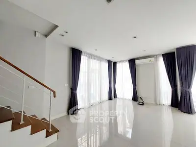 Spacious modern living room with elegant curtains and staircase, perfect for stylish living.