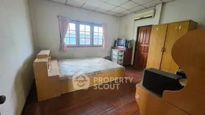 Cozy bedroom with wooden flooring, featuring a bed, wardrobe, and air conditioning unit.