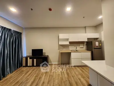 Modern open-layout kitchen and living area with sleek cabinetry and wood flooring.
