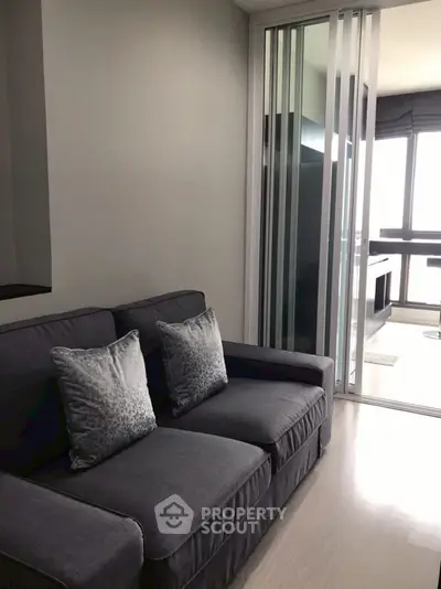Modern living room with sleek sliding glass doors and stylish gray sofa.