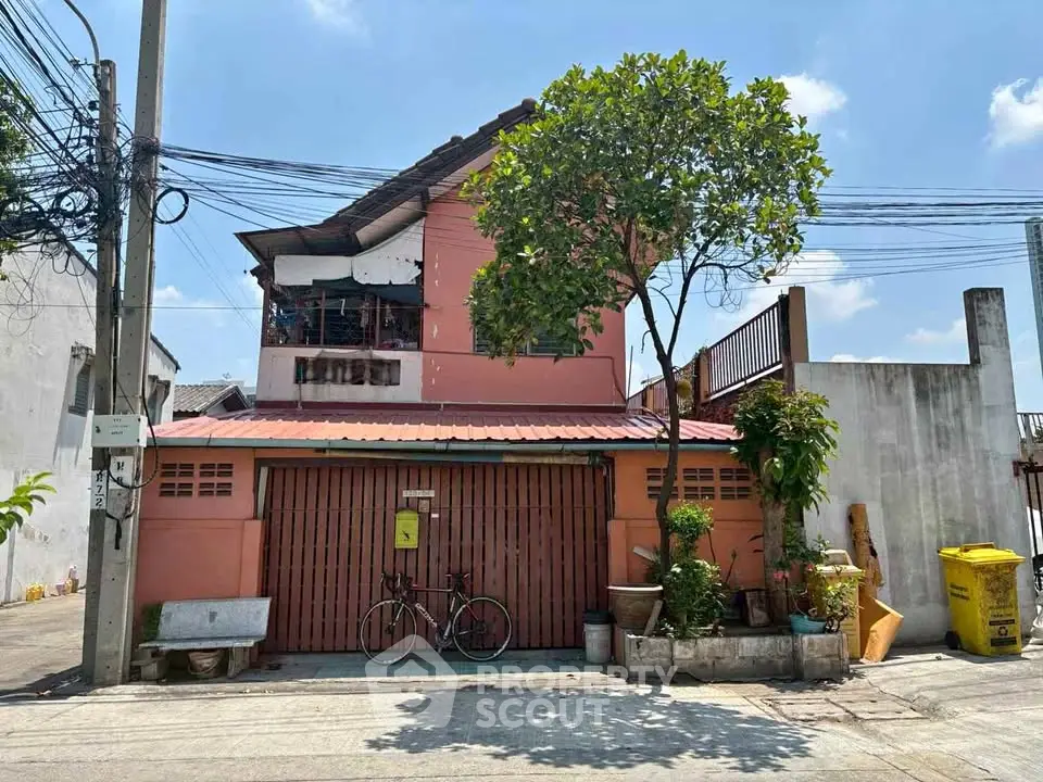 Charming two-story house with a gated entrance and lush greenery in a serene neighborhood.