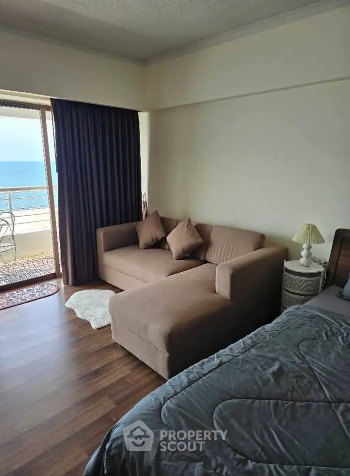 Cozy bedroom with ocean view and balcony access, featuring a comfortable sofa and elegant decor.