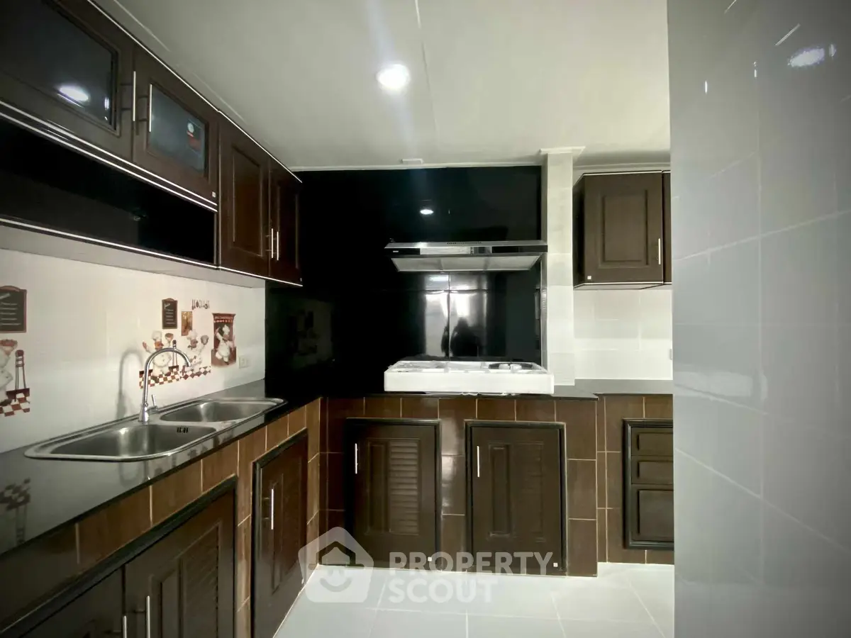 Modern kitchen with dark cabinets and sleek appliances in a stylish home.