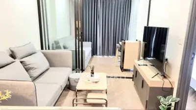 Modern living room with stylish furniture and large TV, featuring elegant decor and natural light.
