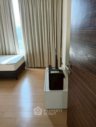 Modern bedroom with wooden flooring and large windows with curtains