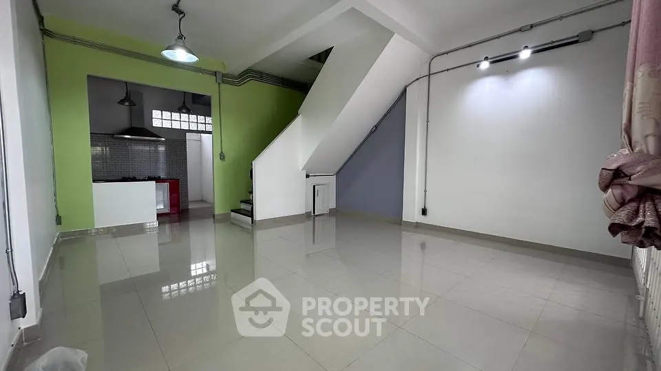 Spacious open-plan living area with modern kitchen and staircase, ideal for contemporary living.