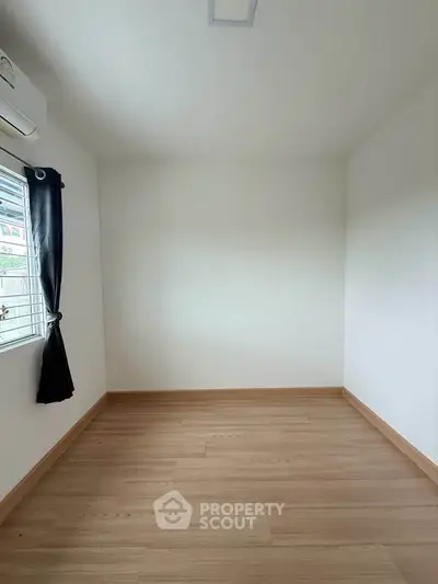 Spacious empty room with wooden flooring and a window, perfect for customization.