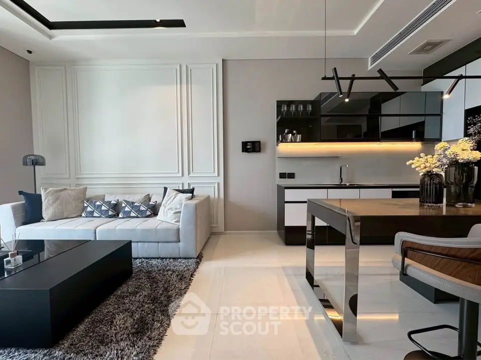 Modern living room with sleek kitchen, elegant decor, and cozy seating area.