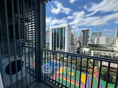 Stunning city view from a high-rise balcony overlooking vibrant sports courts and modern skyscrapers.