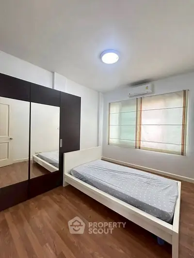 Spacious bedroom with modern furnishings and ample natural light, featuring a sleek wardrobe and cozy bed.