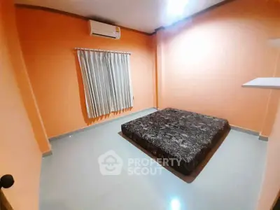 Minimalist bedroom with orange walls and air conditioning unit.