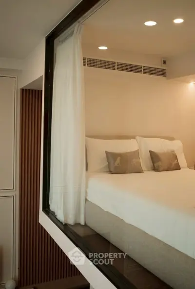 Modern bedroom with elegant decor and large window, featuring cozy bedding and ambient lighting.