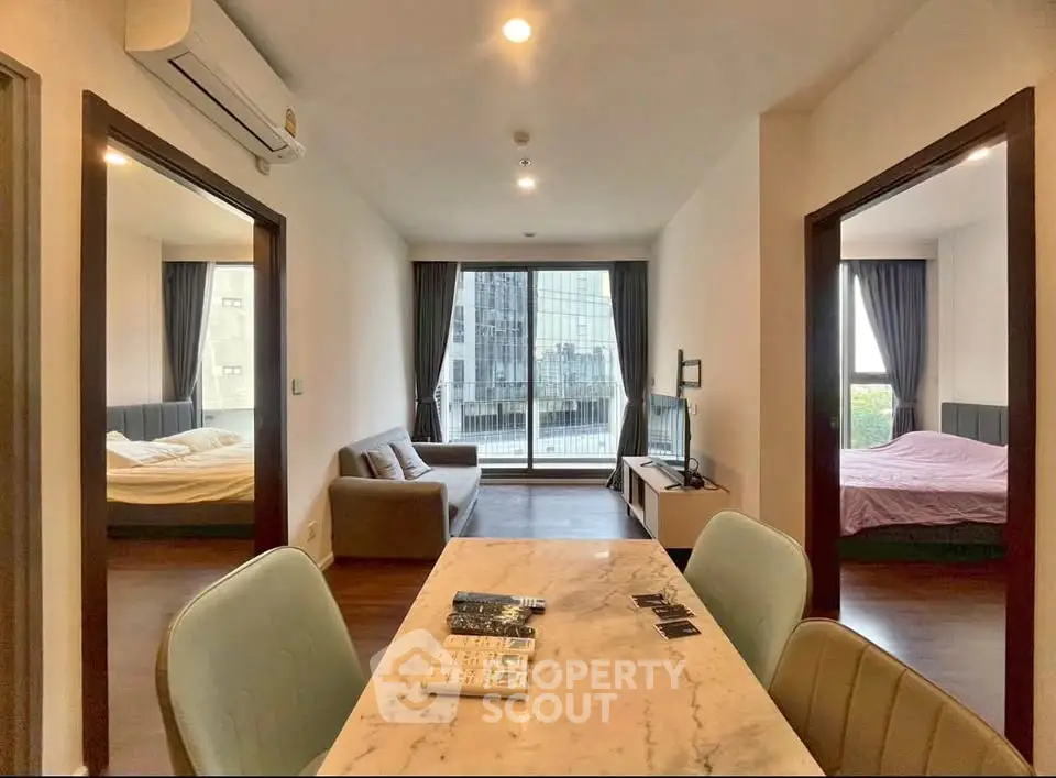 Modern apartment interior with open living and dining area, featuring two bedrooms and city view.