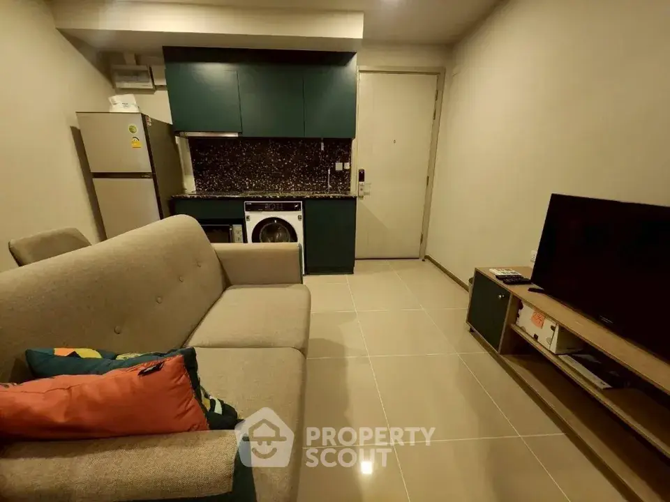 Cozy living room with modern kitchenette and washing machine in compact apartment.