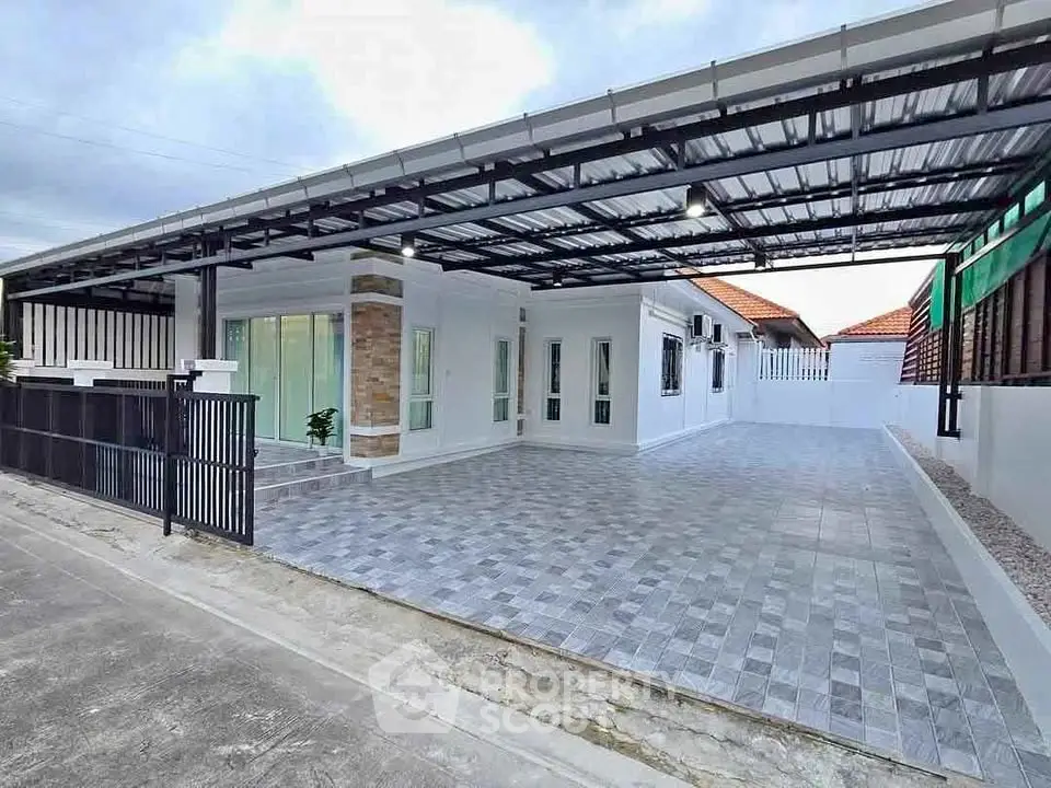 Modern single-story house with spacious tiled driveway and covered carport.