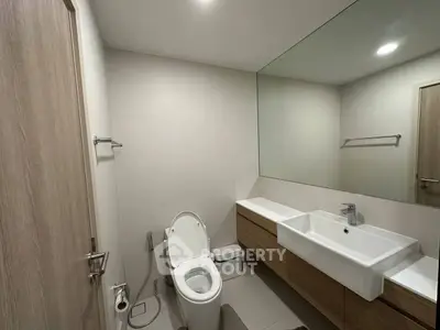 Modern bathroom with sleek fixtures and large mirror in a contemporary home.