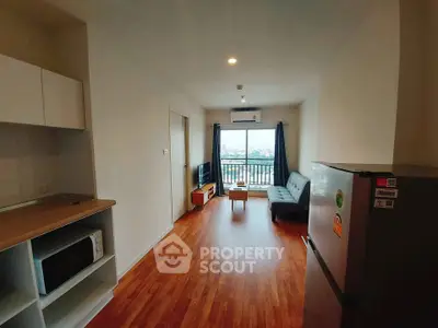 Modern living room with wooden flooring, cozy sofa, and large window offering city views.