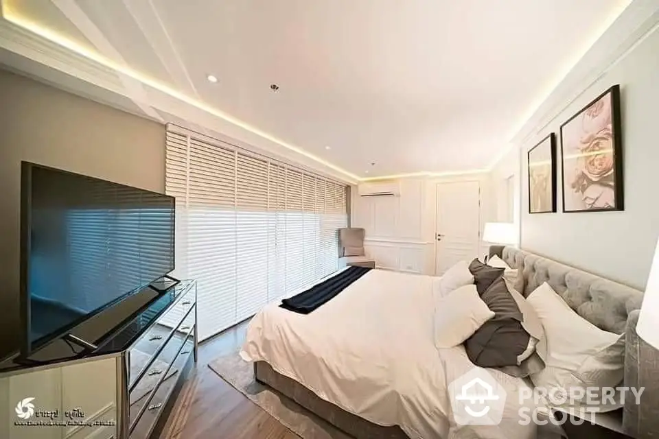 Spacious and elegantly furnished bedroom with a large comfortable bed, modern flat-screen TV, and ambient lighting, perfect for relaxation.