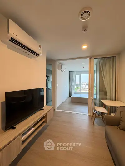 Modern living room with sleek furniture and large TV, leading to a bright bedroom with city view.
