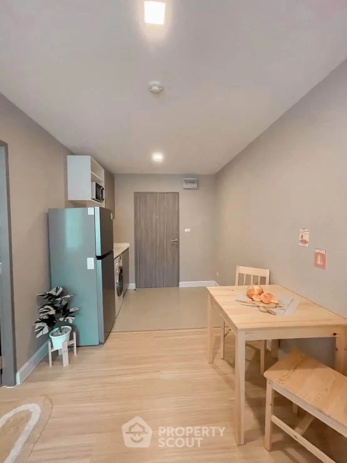 Modern kitchen with dining area, featuring a fridge, washing machine, and wooden table set.
