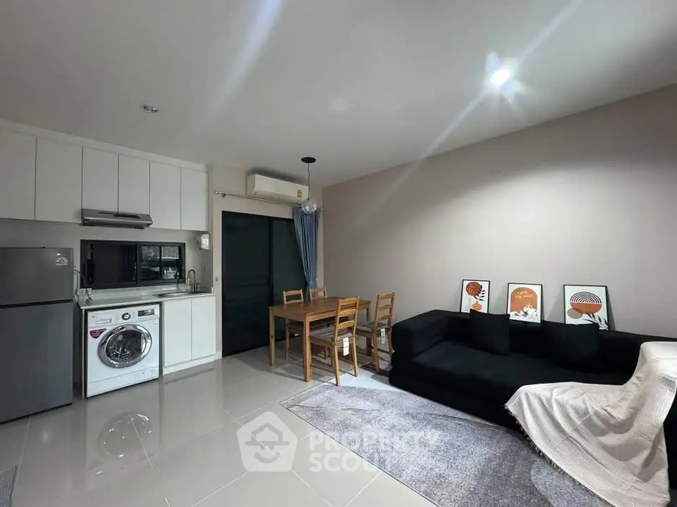 Modern open-plan living room with kitchen and dining area, featuring sleek appliances and stylish decor.