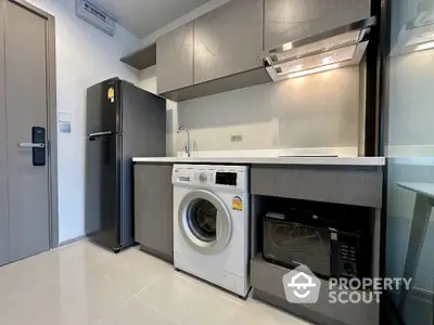 Modern kitchen with sleek appliances and washing machine in compact layout.