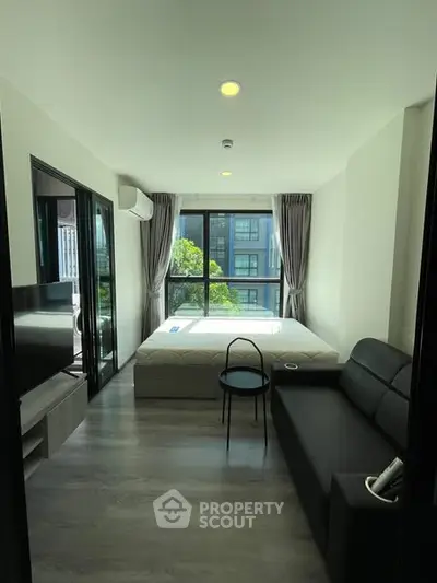 Modern studio apartment with large windows and sleek furnishings