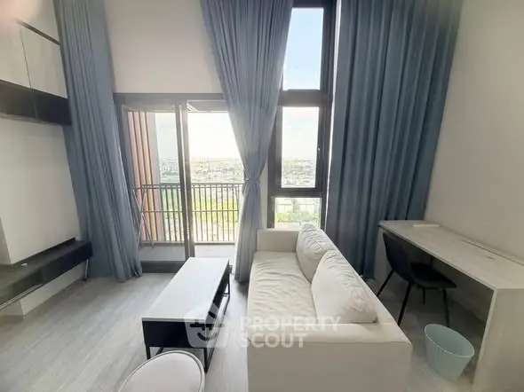Modern living room with high ceiling and balcony view, featuring elegant blue curtains and stylish furniture.