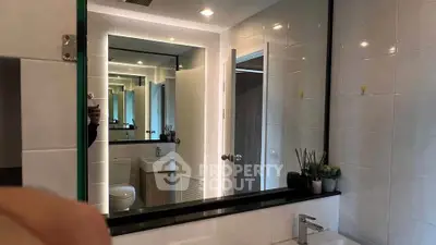 Modern bathroom with sleek design and large mirror reflecting elegant fixtures.