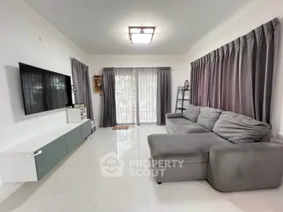 Spacious living room with modern gray sofa and large TV, perfect for relaxation.