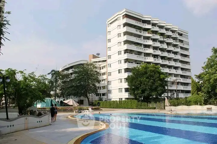 Luxurious apartment building with a stunning outdoor pool and lush greenery.