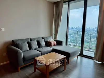 Modern living room with city view and large balcony in high-rise apartment.