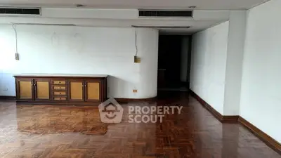 Spacious empty room with wooden flooring and built-in cabinet