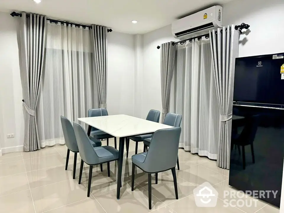 Modern dining area with sleek table and chairs, featuring elegant curtains and air conditioning.