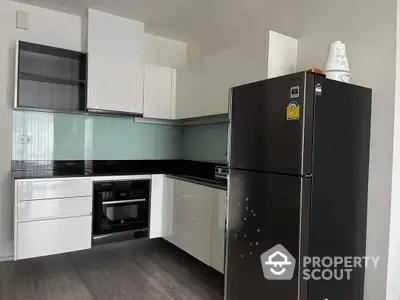 Modern kitchen with sleek black appliances, glossy white cabinetry, and a dark countertop, perfect for culinary enthusiasts.