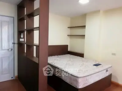 Cozy bedroom with built-in shelves and comfortable mattress in modern apartment.