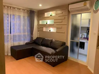 Cozy living room with modern decor and air conditioning, featuring a comfortable black sofa and stylish wall accents.
