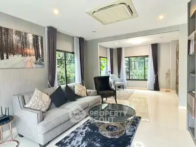 Elegant living room with modern decor and large windows offering lush garden views.
