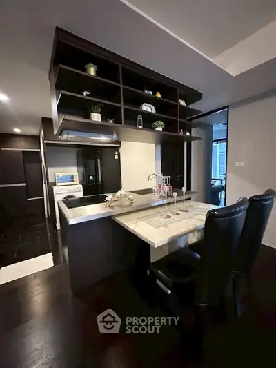 Modern kitchen with sleek design and open layout, featuring dark cabinetry and stylish countertops.
