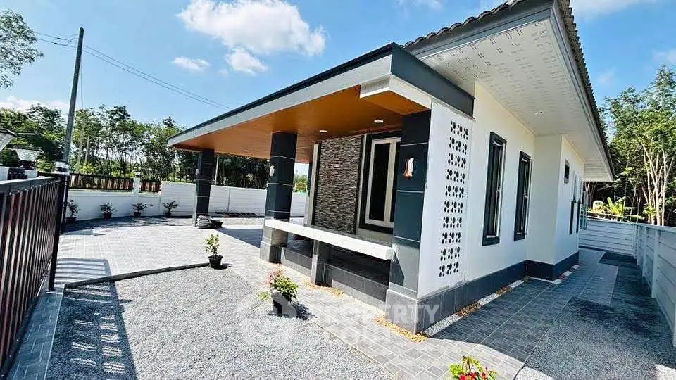Modern single-story house with spacious driveway and contemporary design.