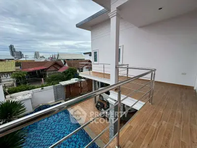 Spacious balcony overlooking a serene pool with cityscape views, perfect for relaxation and entertainment.