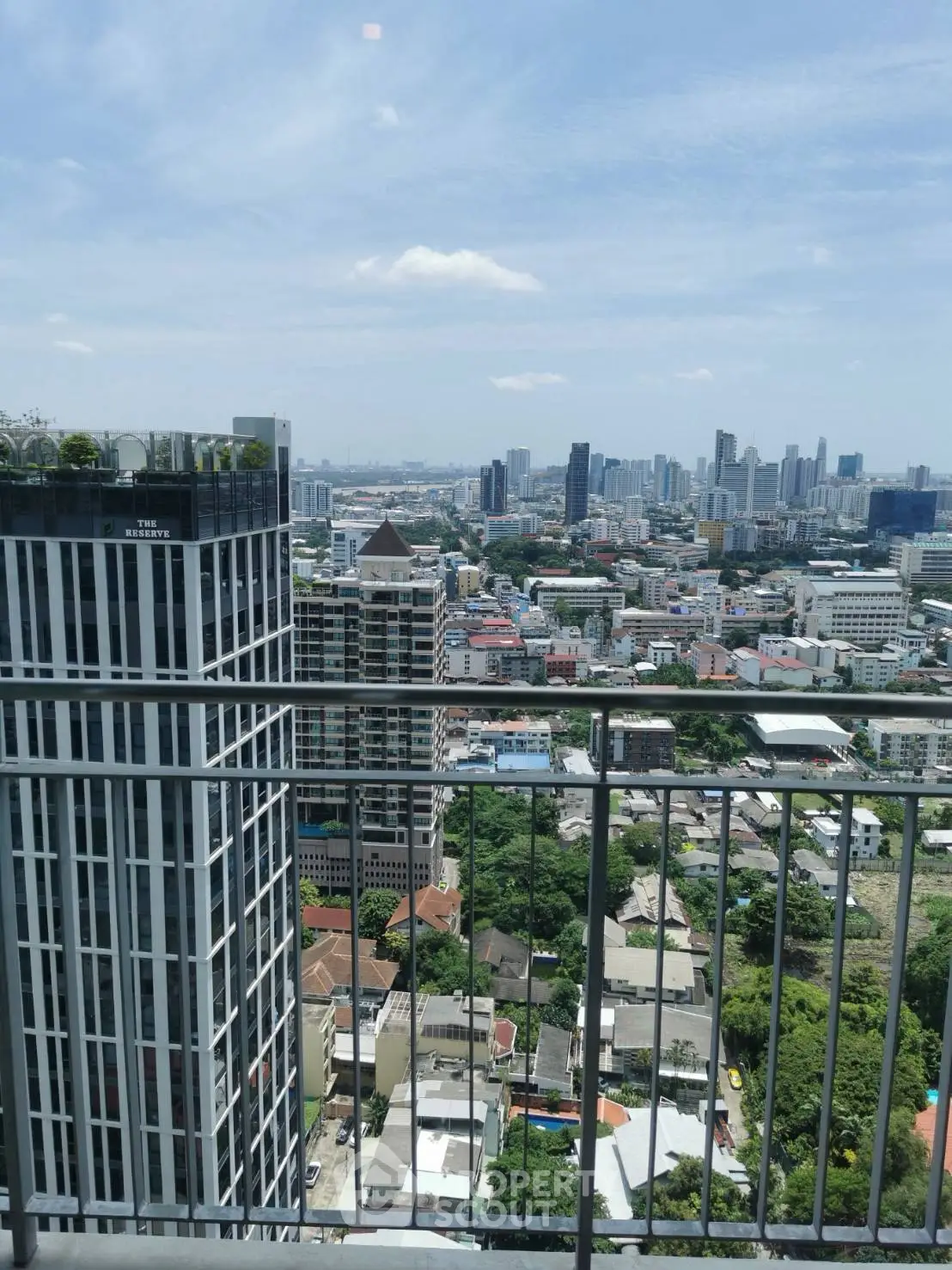 Stunning cityscape view from a high-rise balcony showcasing urban skyline and lush greenery.