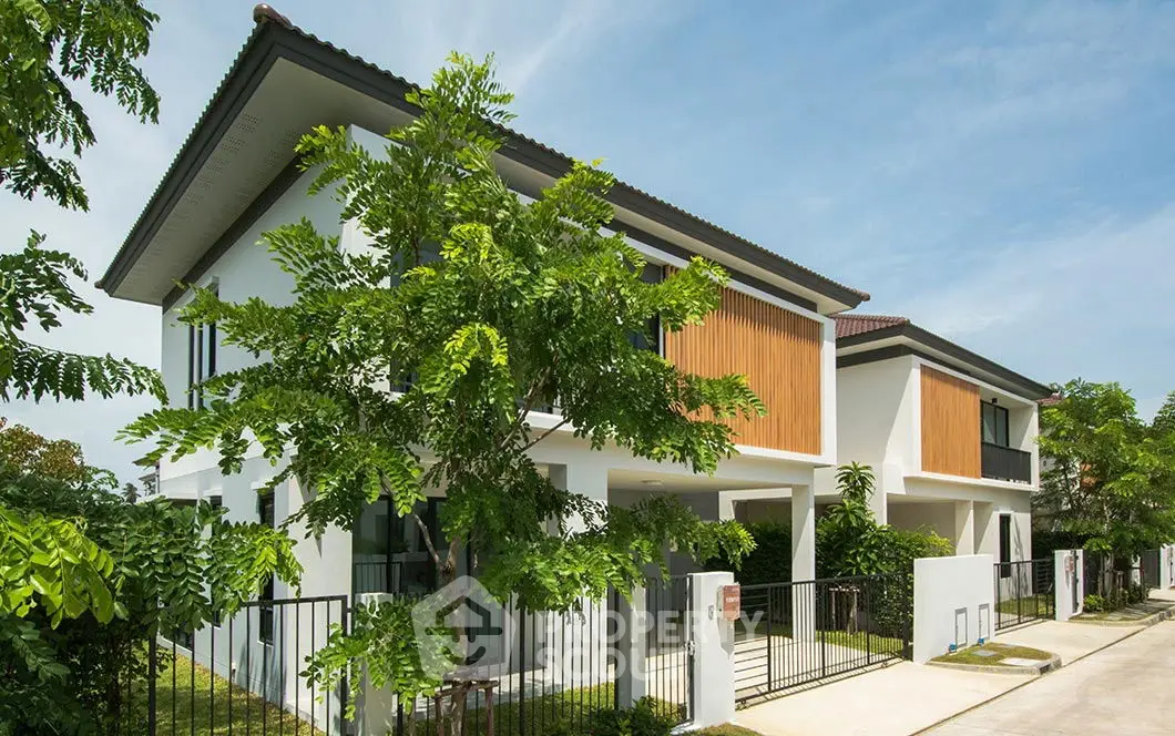 Modern two-story house with lush greenery and sleek design in a serene neighborhood.