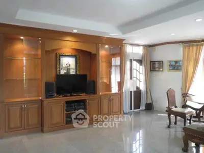 Spacious living room with elegant wooden entertainment center and natural light