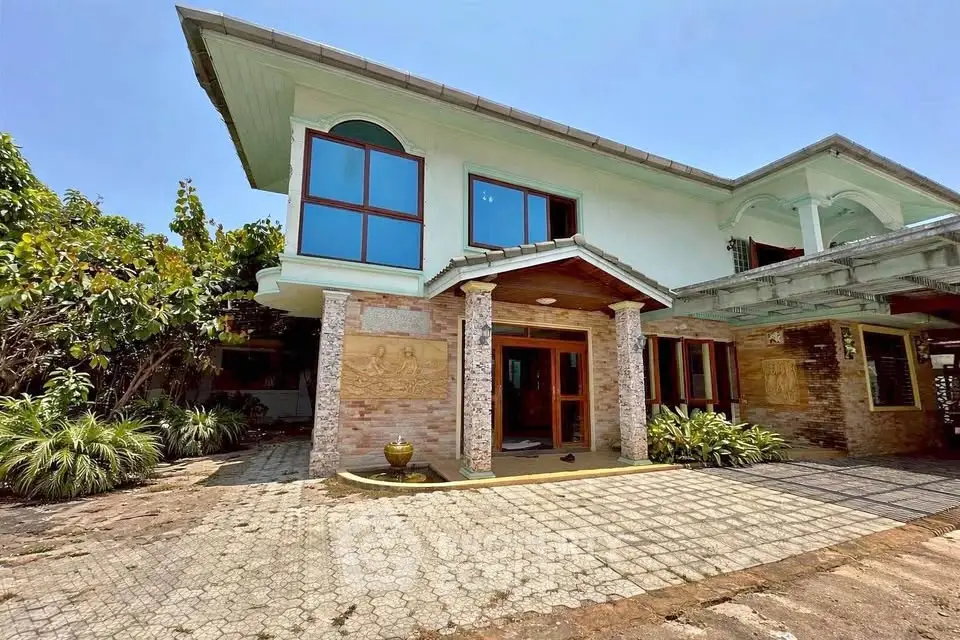 Stunning two-story house with unique architectural design and spacious driveway, surrounded by lush greenery.