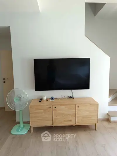 Modern living room with minimalist TV setup and wooden cabinet