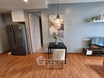 Modern living room with wooden flooring, stylish decor, and sleek appliances.